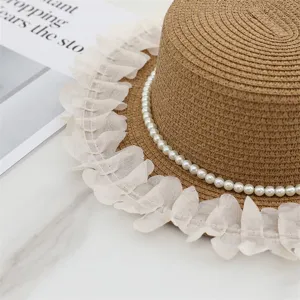 Primo piano di elegante cappello di paglia con fascia di perle e bordo volant trasparente.