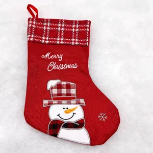 Close-up of red Christmas stocking featuring plaid cuff, snowman embroidery and festive text.