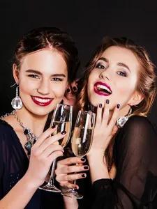 Close-up detail shot of sparkling disco ball earrings worn by models with champagne glasses.