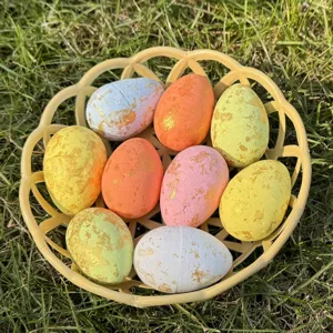 Close-up detail view of colorful speckled Easter eggs in a basket on outdoor grass.