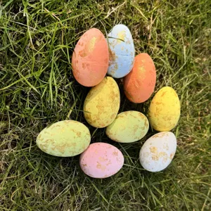 Close-up view of decorative Easter eggs with gold foil speckles scattered on green grass.