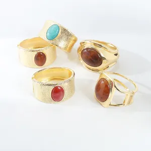 Close-up detail of vintage chunky gold metal bracelets with colorful resin stones and textured finish.