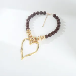 Chaîne de clavicule perlée style doux avec un grand pendentif cœur creux irrégulier.