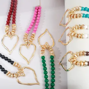 Gros plan détaillé montrant des colliers de perles en acrylique coloré avec grands cœurs creux.