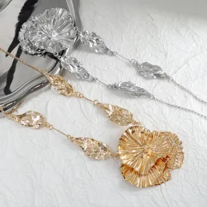 Detailed shot of exaggerated metallic flower and leaf pendant necklaces in gold and silver.