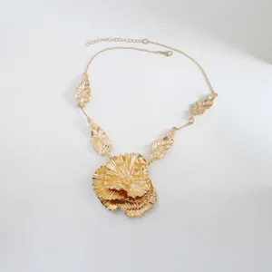 Detailed view of the gold statement necklace featuring layered flower and leaf pendants.