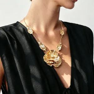 Exaggerated metallic flower pendant necklace with leaf chain details worn on model