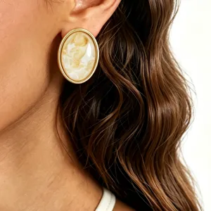 Close-up detail shot of elegant oval resin inlaid metal frame earrings with vintage style.