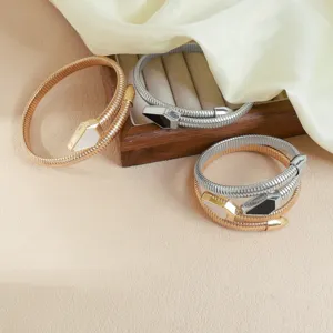 Primer plano de pulseras flexibles de serpiente en oro y plata con detalle de aceite.