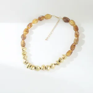 Close-up detail of the vintage resin and gold bead necklace, showing textured geometric elements.