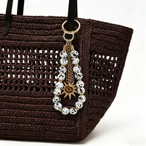 Bijou de sac perlé fait main avec perles mouchetées, chaînes dorées et pendentif soleil élégant.