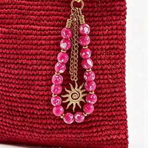 Gros plan détail du pendentif de sac en perles acryliques colorées avec breloque soleil.