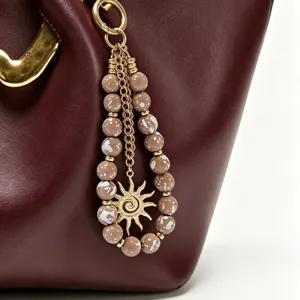 Vue détaillée du charm de sac en perles acryliques colorées avec pendentif soleil.