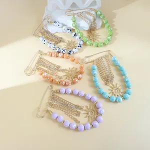 Détail d'épingle de sûreté perlé coloré avec pendentif soleil et pampilles pour accessoire créatif.
