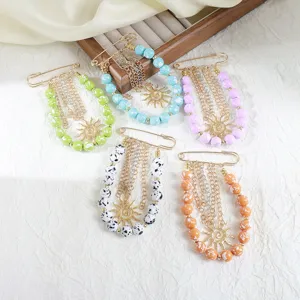 Gros plan sur les détails de pendentifs épingles de sûreté en perles acryliques colorées.