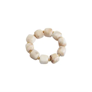 Acrylic marbled beaded bracelet detail, beige geometric block beads with golden spacer accents.