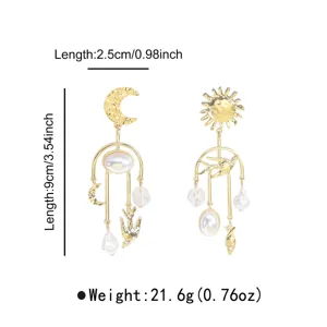Nahaufnahme der goldenen asymmetrischen Ohrringe mit Sonne, Mond, Perle und fliegender Taube.