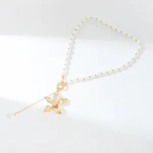 Exquisite pearl necklace detail featuring a golden frangipani flower pendant and chic OT clasp.