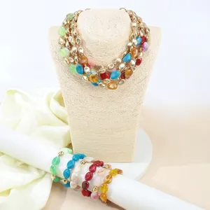 Vista dettagliata di collana multistrato e bracciali con perline in acrilico irregolare fatte a mano.