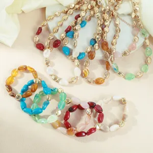 Primo piano di collane e bracciali con perline acriliche irregolari colorate e metallo.
