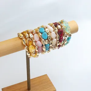 Bracciali con perline irregolari in acrilico colorato impilati su un supporto in legno.