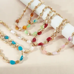 Vista ravvicinata dettagliata di gioielli con catena di moda in resina colorata e perle oro.