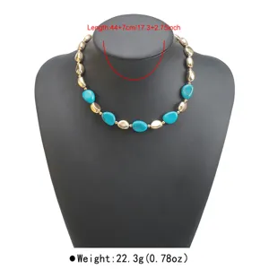 Dettaglio della collana di perle con pietre turchesi e sfere metalliche dorate eleganti.