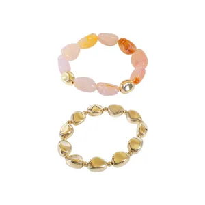 Vista dettagliata del set di bracciali di perle in resina acrilica e metallo dorato.