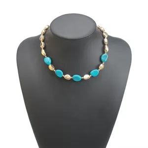 Primo piano della collana di perle turchesi e dorate irregolari vintage su manichino nero.