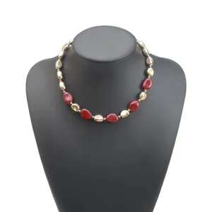 Dettaglio in primo piano della collana di perle rosse e oro irregolari con finiture.