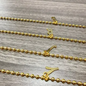 Gedetailleerd overzicht van 18k vergulde koperen kogelketting armband met stijlvolle letterbedels.