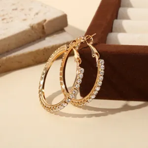 Detailopname van luxe vergulde strass-steen ingelegde C-vormige creolen oorbellen, elegant sieradenstuk.