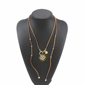 Collar largo de ante bohemio con colgantes dorados de sol y luna, joyería boho.