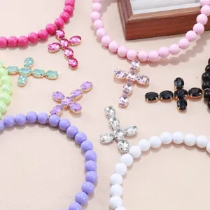 Primo piano dettagliato della collana di perline colorate con croce in strass scintillanti.