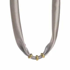 Detailed close-up of the elegant grey fabric ribbon necklace featuring three polished golden rings.