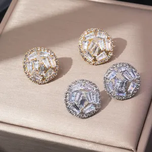 Detailopname van ronde geometrische zirkonia oorknopjes met gouden en zilveren metalen afwerking.