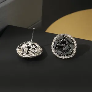 Detailopname van ronde oorknopjes met strass-steentjes en zwarte geometrische stenen.