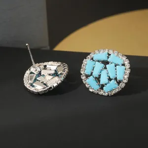 Detailopname van de ronde oorknopjes met blauwe steen en sprankelende zirkonia kristallen.