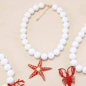Dettaglio della collana di perle bianche con ciondolo stella marina rossa, stile mare.
