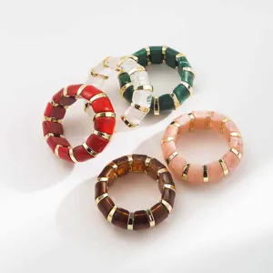 Gros plan sur des bracelets joncs segmentés en résine colorée, détail de bijoux tendance.