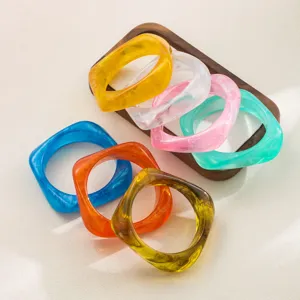 Détail de bracelets jonc en résine irrégulière colorée, bijoux de mode géométriques acryliques.