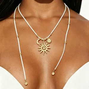 Collar largo bohemio con dijes de sol y luna, cordón blanco y cuentas doradas.