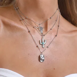 Close-up of a multi-layer western cowboy necklace with bull skull and cactus pendants.
