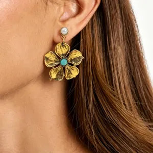 Close-up view of vintage gold flower earrings featuring pearl studs and turquoise centers.