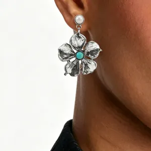 Detailed close-up shot of vintage silver flower earring with pearl and turquoise stone.