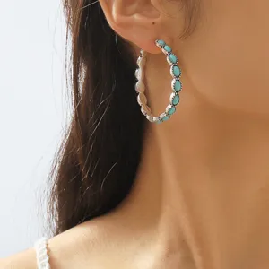 Detailed close-up shot of vintage silver turquoise hoop earrings worn on ear, western style.