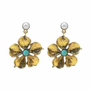 Close-up detail of vintage gold-tone flower earrings with pearl studs and turquoise stones.