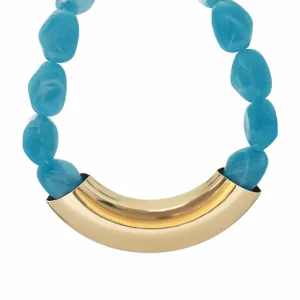 Close-up of retro geometric blue resin beaded necklace with exaggerated curved gold metal tube.