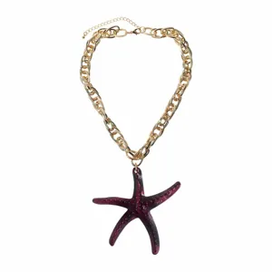 Close-up view of a gold chunky chain necklace featuring a dark purple resin starfish pendant.