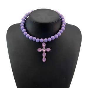 Primo piano della collana girocollo con perline viola e ciondolo a croce di cristallo.